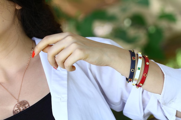 A woman wearing a white shirt and a white shirt holds a bracelet with the word love on it.