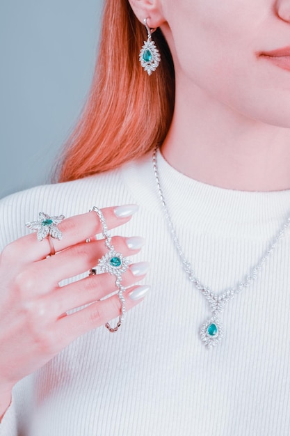 A woman wearing a white sweater with a ring that says " turquoise ".