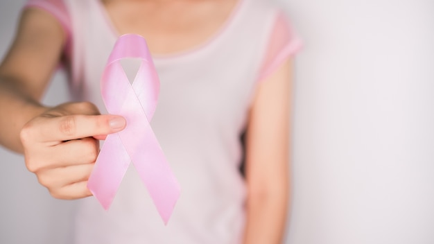 Woman wearing a white t-shirt and holding pink ribbon