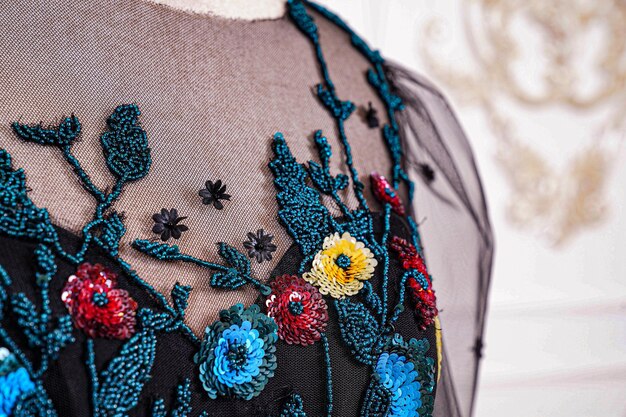 Photo a woman wears a black dress with a blue and red flower on it.