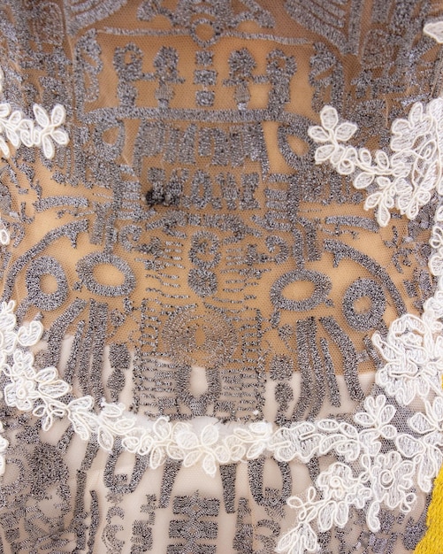 A woman wears a lace dress with a yellow flower in the background.
