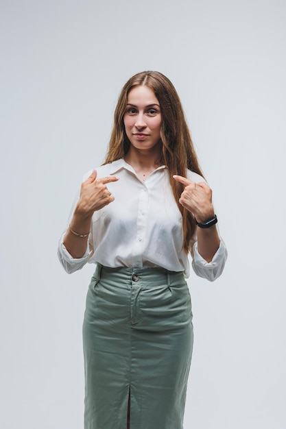 A woman wears a white blouse and skirt on a gray background emotions on a woman's face Elegant look positive woman Model in casual clothes Summer spring or autumn street look