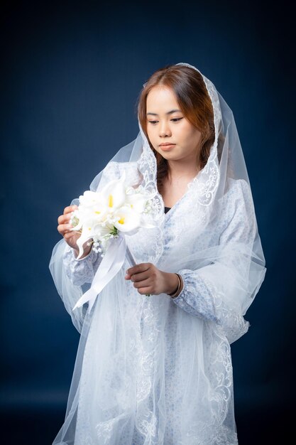 A woman in a wedding dress holds a bouquet of flowers.