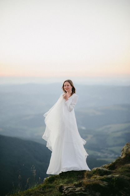 Woman in a wedding dress runs across the field toward the mountains