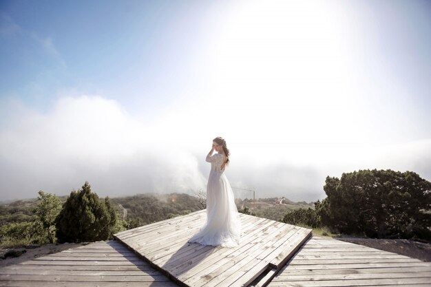 A woman in a wedding dress stands alone on a wooden floor in an open area