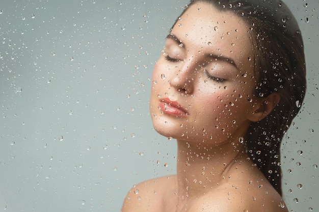 Woman behind the wet glass Focus on the droplets