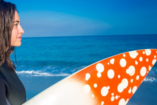 Woman in wetsuit with a surfboard on a sunny day