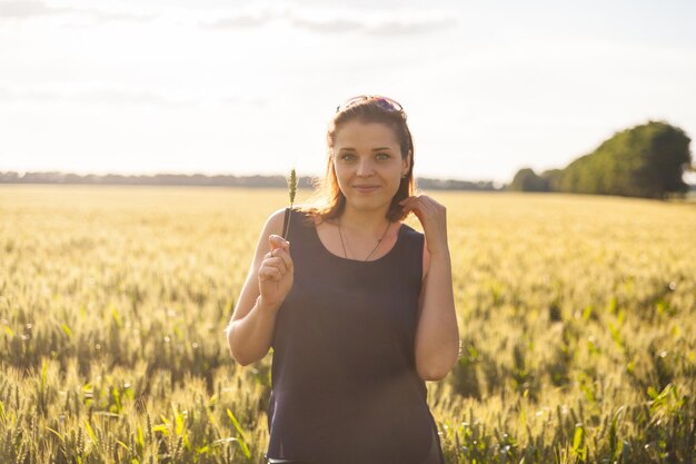 Woman in a wheat field on the background of the setting sun