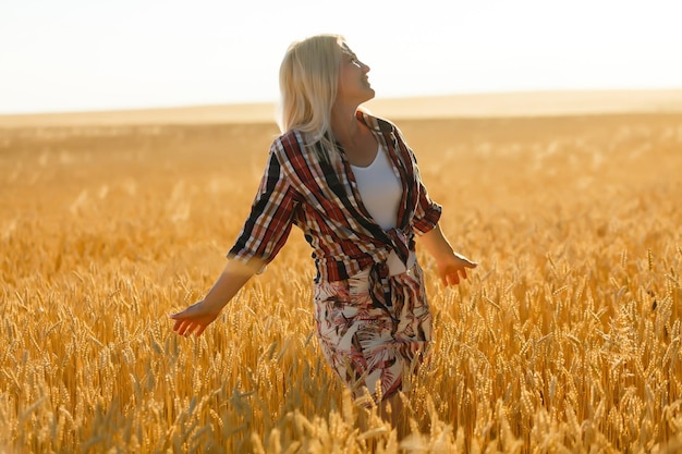 Woman in a wheat field on the background of the setting sun