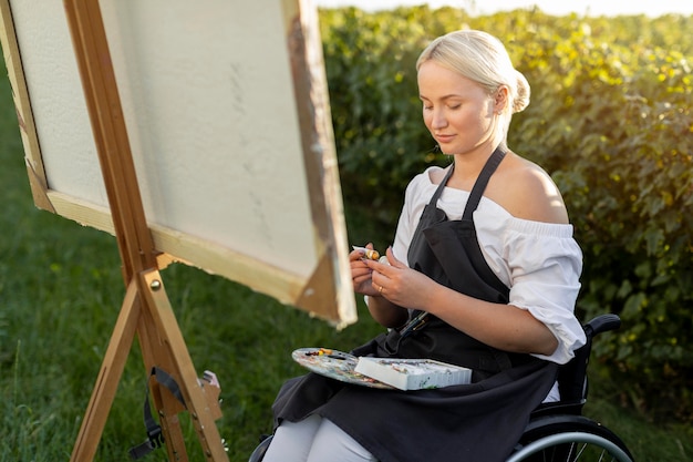 Woman in wheelchair painting in nature