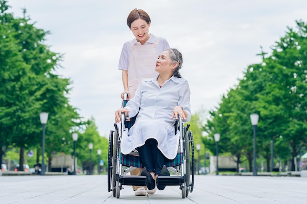 車いすの女性とエプロンの若い女性の世話をする