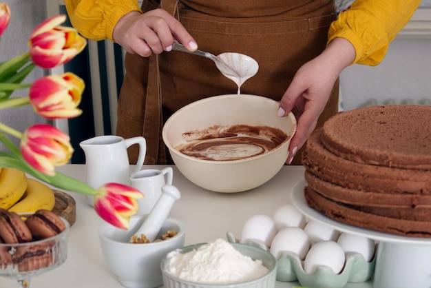 Woman whipping cream with a spoon in a biscuit cake bowl in a cozy setting in the kitchen