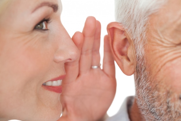 Woman whispering secret into a man&#039;s ear