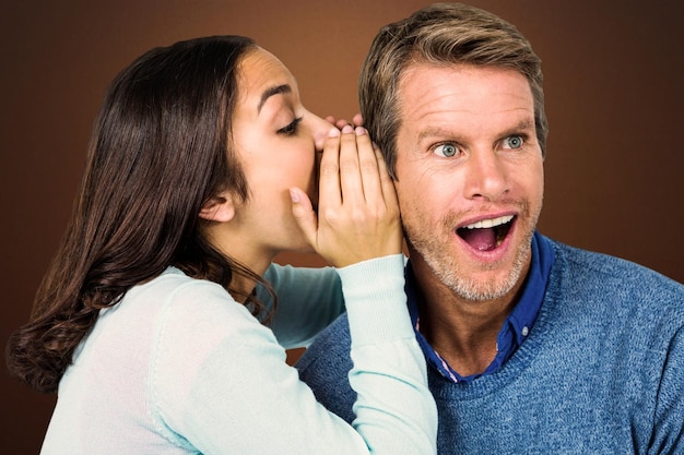 Woman whispering secret with man against shades of brown