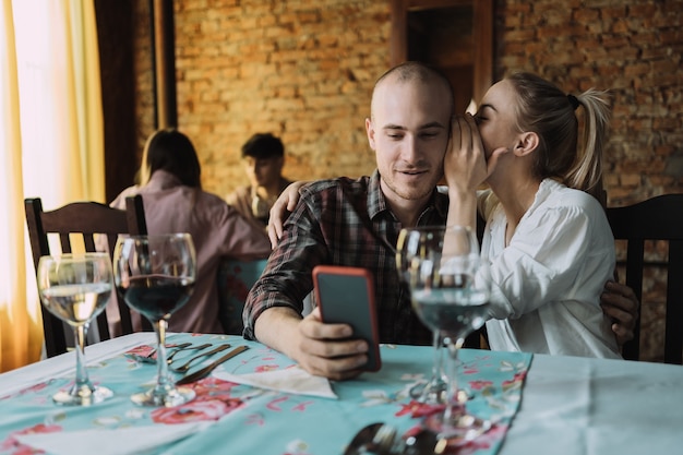 Woman whispers something in her boyfriends ear in the restaurant