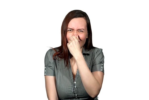 A woman on a white background clamps her nose and wrinkled, as if from a hideous smell