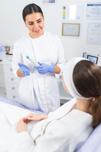 Женщина в белом халате слушает объяснения косметолога перед косметической процедурой