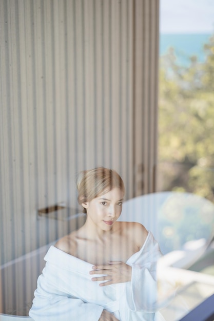 Woman in white bathrobe sitting on bathtub.