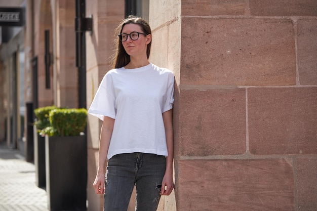 街で眼鏡をかけている白い空白のTシャツの女性