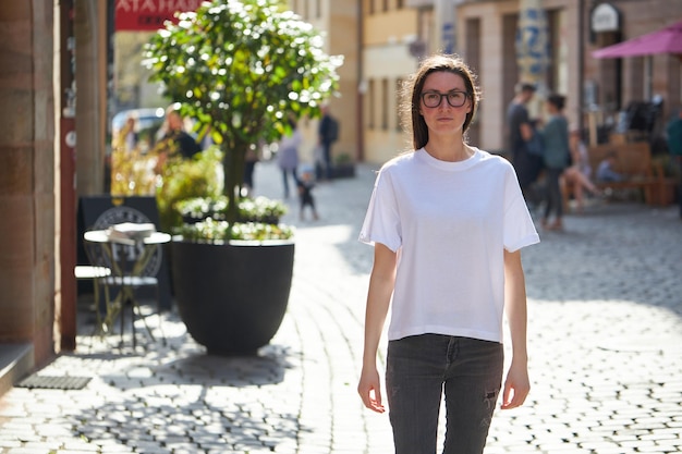 Woman in white blank tshirt wearing glasses in the city