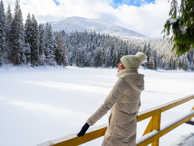Woman in white clothes enjoying frozen lake Synevyr