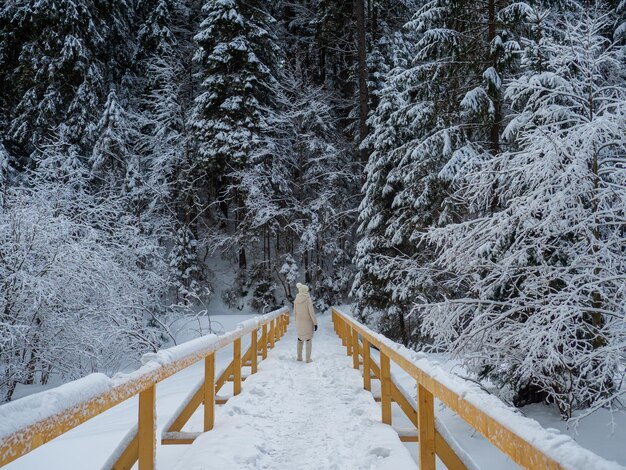 Woman in white clothes enjoying winter forest