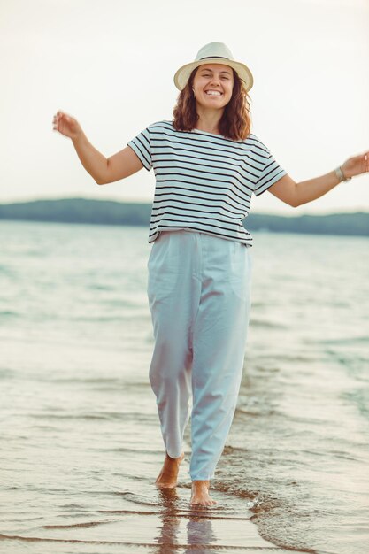 海のビーチを歩く白い服を着た女性