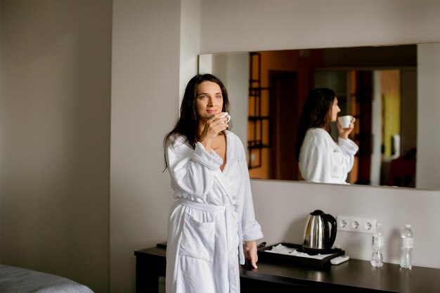 a woman in a white coat in a hotel room