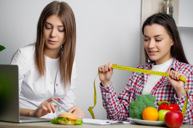 Woman in the white coat nutritionist writes a healthy diet program for weight loss