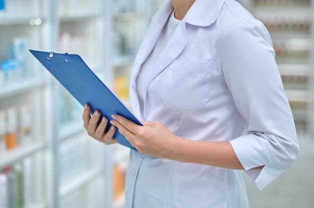 Woman in white coat with blue folder