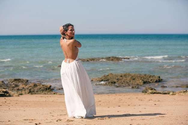 Женщина в белом платье и снова в воздухе, стоя на пляже