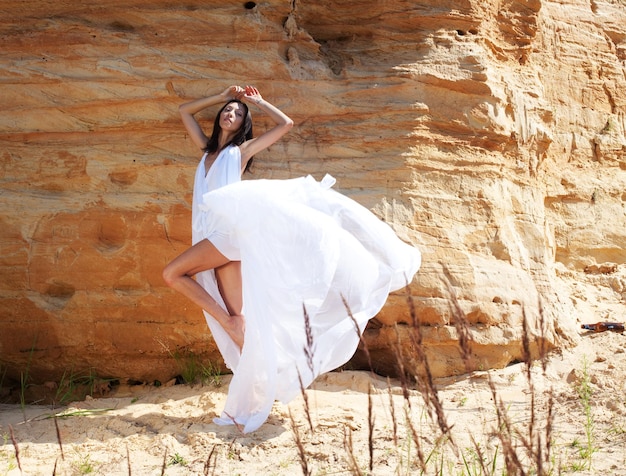 Woman in white dress dancing on the desert