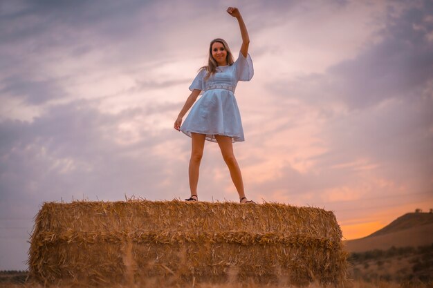 Woman in a white dress in a field of dry straw