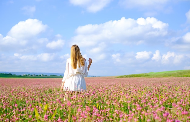 Photo woman in white dress on flowered sainfoin field woman on a blooming field of pink