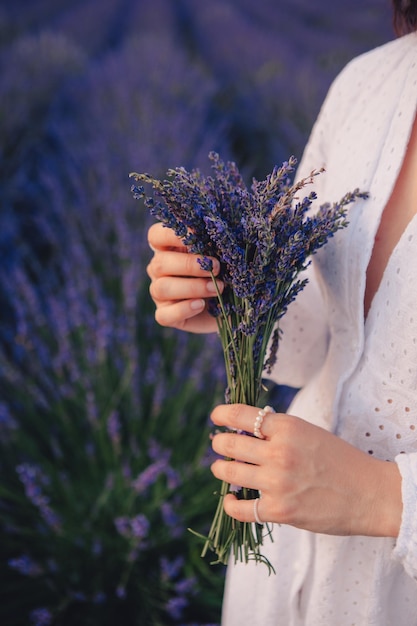 Woman in white dress holding bouquet of lavender flowers close up