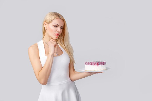 Woman in white dress holding cake