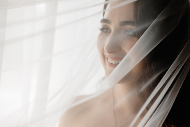 A woman in a white dress is standing behind a sheer curtain