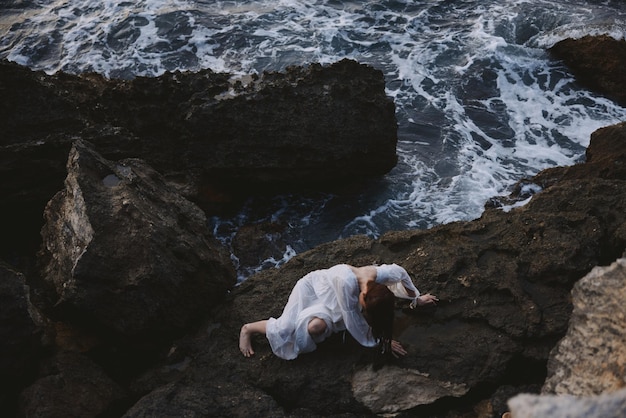 Woman in a white dress lying on a stone in a white dress unaltered High quality photo