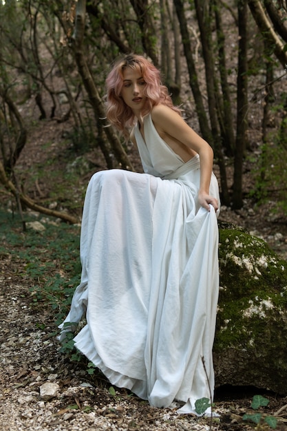 A woman in a white dress in the middle of the forest