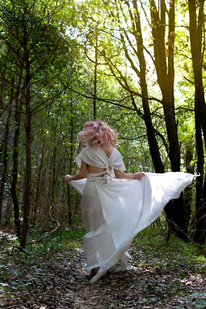 A woman in a white dress in the middle of the forest.