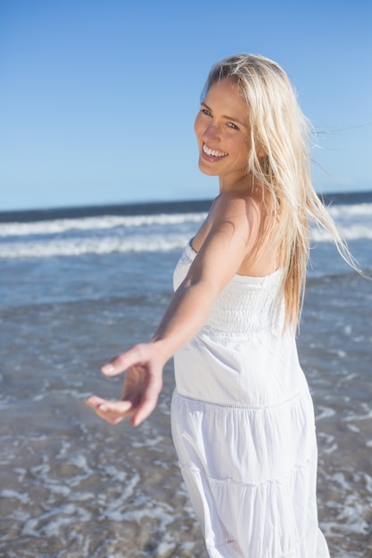 Woman in white dress offering her hand on the beach