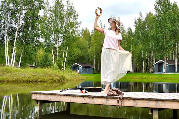 Woman in a white dress on a pier with a guitar