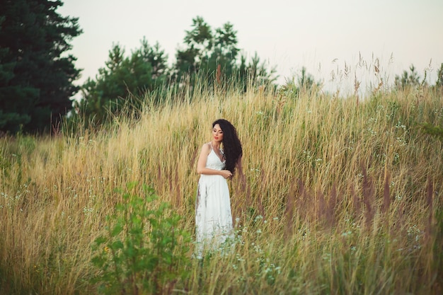 Woman in a white dress posing in a field