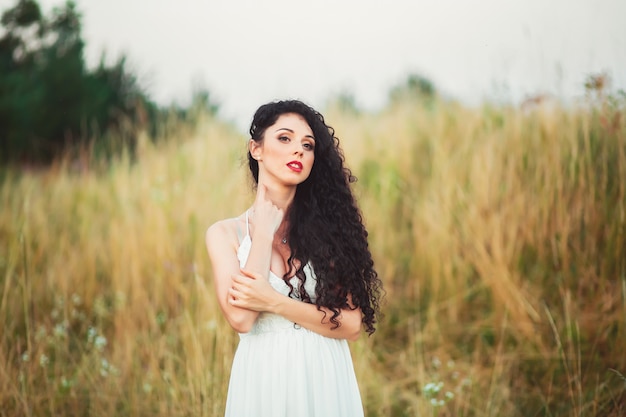 Woman in a white dress posing in a field