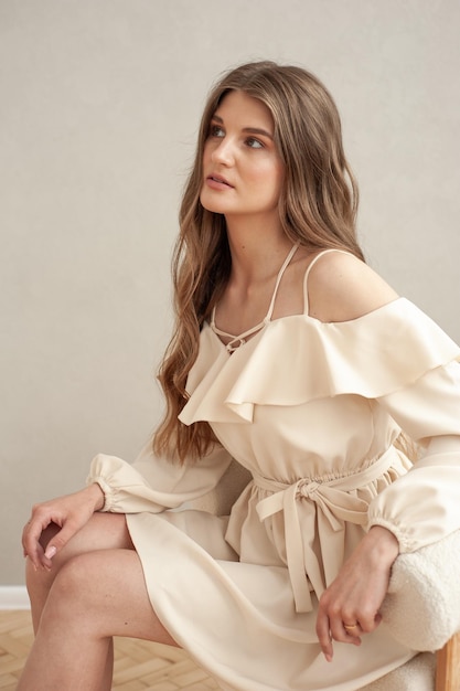 A woman in a white dress sits on a chair