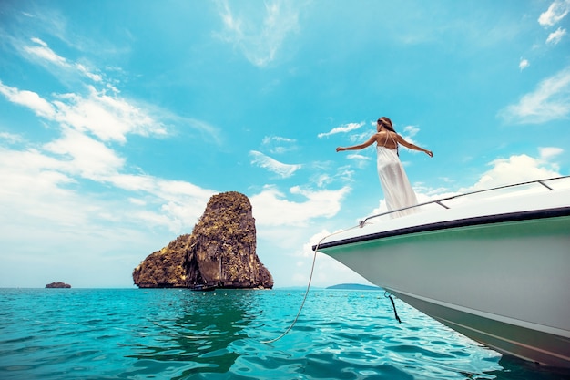 Woman in a white dress standing on edge of yacht