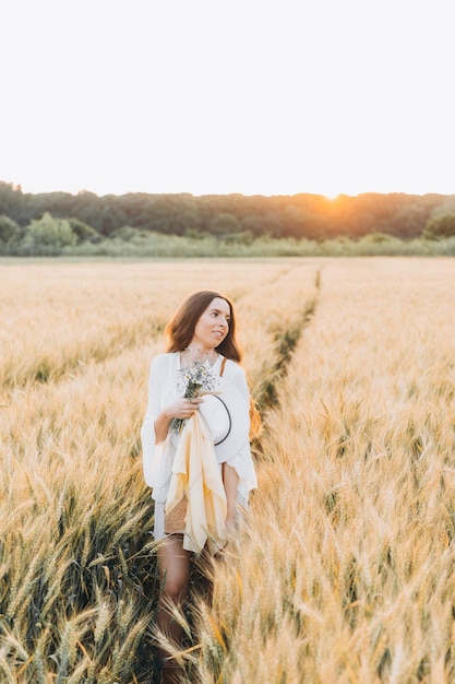 woman in a white dress and a white hat in a wheat field