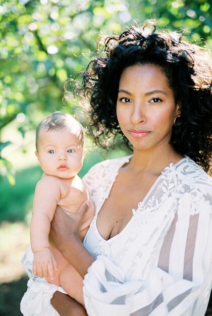 Photo woman in a white dress with a newborn in her arms