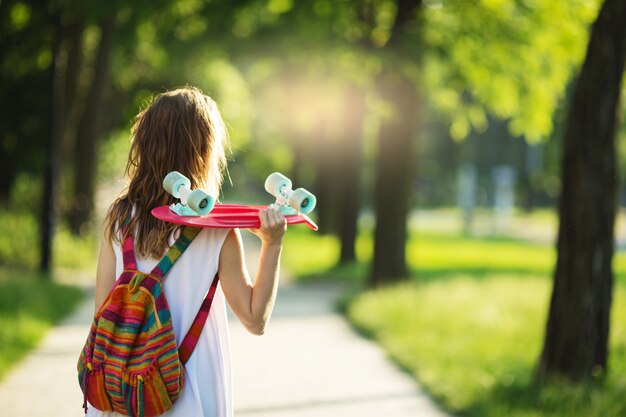 Photo woman in white dress with a pink skateboard