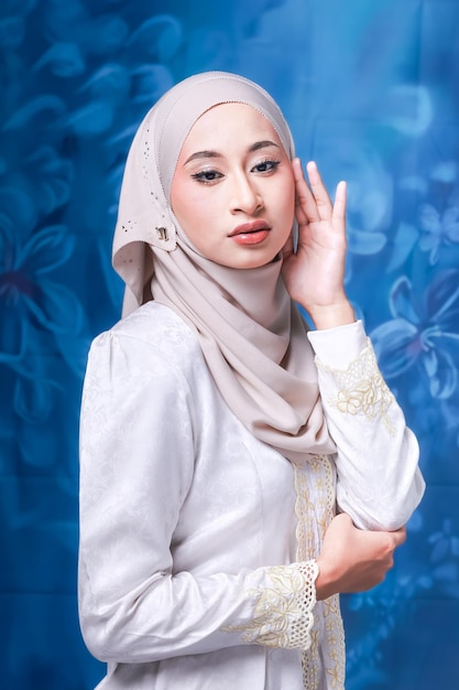 A woman in a white hijab and a blue background